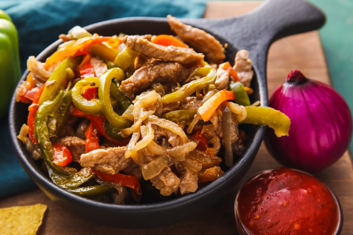 9 Foods You Should Never Order at a Chain Restaurant 4 Frying pan with tasty beef Fajita and sauce on table, closeup
