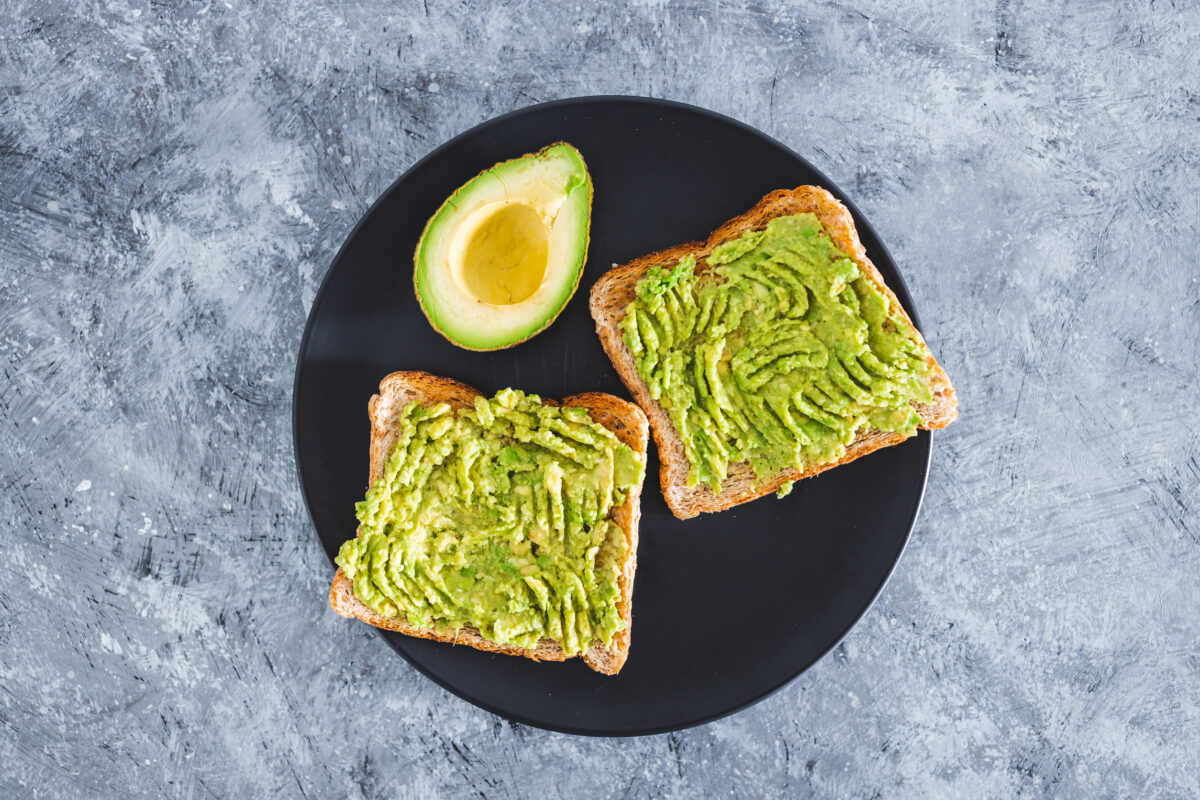 The Truth Behind Overrated Foods 1 basic plant-based smashed avocado toast with half avocado next to it, healthy vegan food recipes