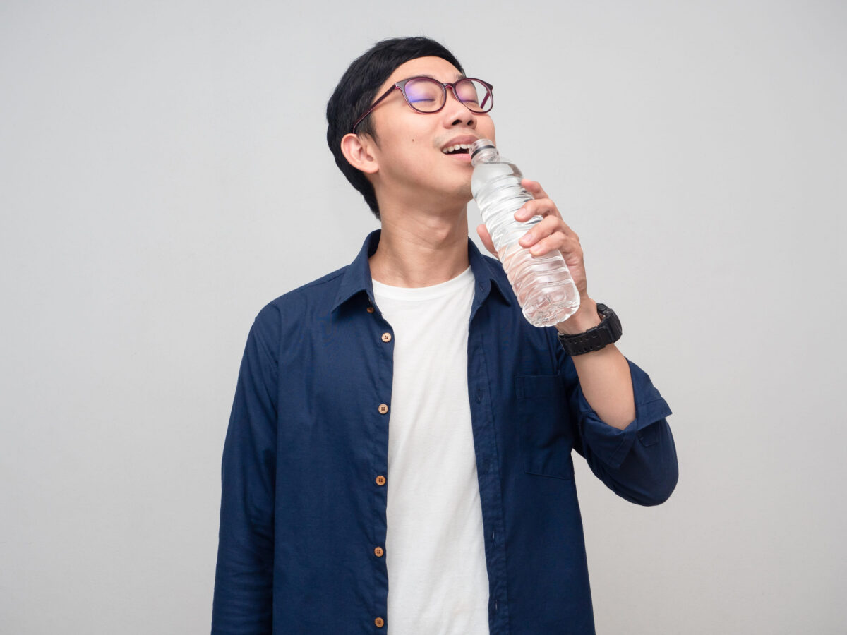 Young asian man wear glasses drinking water isolated