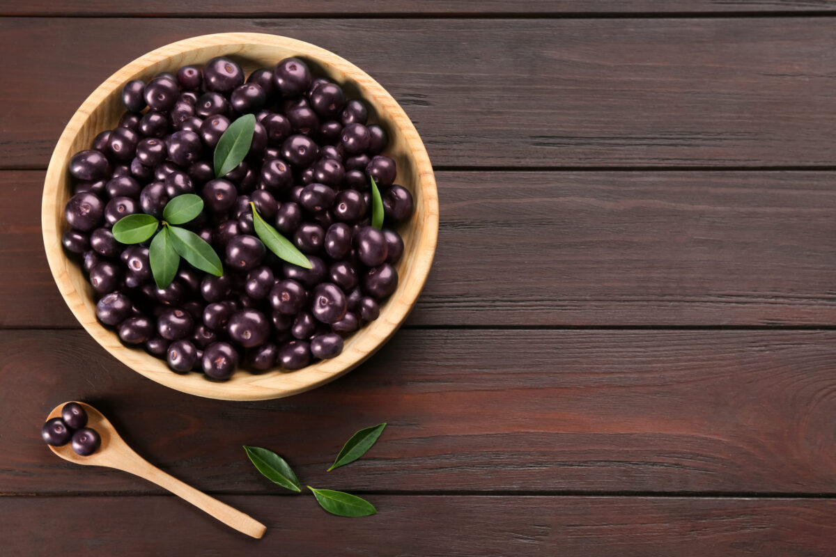These 10 Superfoods Are Actually Super Dangerous for Your Health 1 Tasty acai berries in bowl and spoon on wooden table, flat lay. Space for text