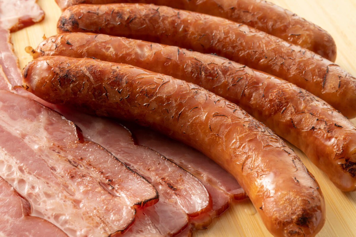 Why These 7 Protein-Packed Foods Are Actually Holding Back Your Fitness Goals 2 smoked sausages on a wooden board, close-up.
Delicious bacon that is fresh and full of flavor