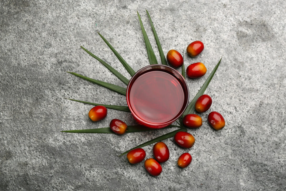 8 Common Cooking Oils You Should Never Use 3 Palm oil in glass bowl, tropical leaf and fruits on gray table, flat lay