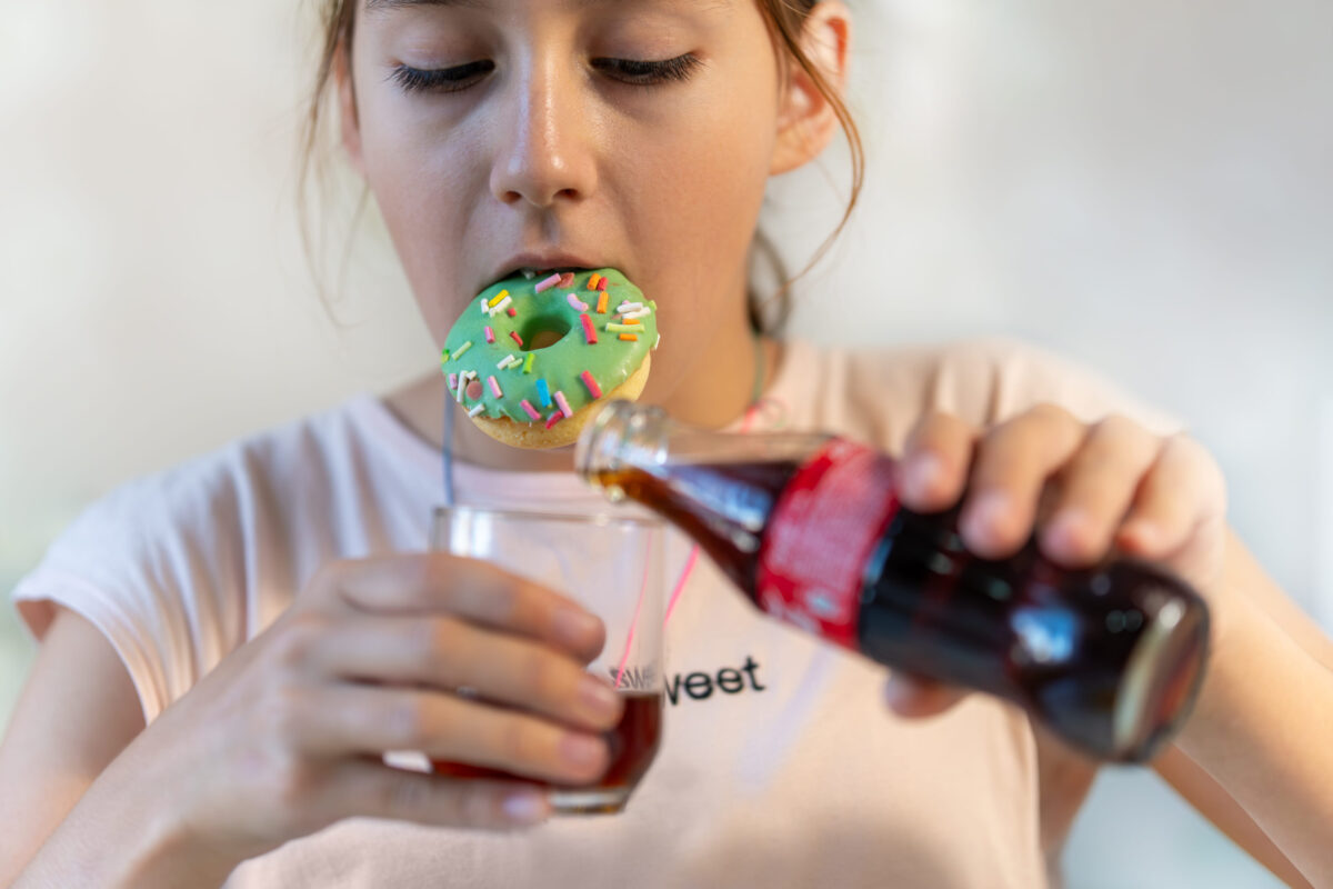These 6 Celebrity-Approved Foods Are Actually Terrible for You 4 Little girl eating donut messily. A sweet cupcake in hand. The girl is eating sweet pastries. an open mouth and a green chocolate donut.
