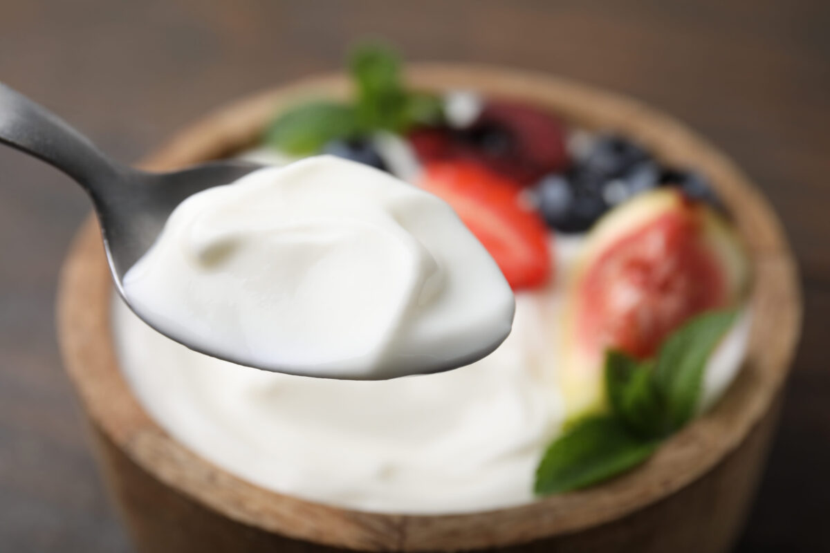 8 Misleading Diet Foods That Are Undermining Your Weight Loss Goals 1 Spoon with tasty yogurt above bowl on table, closeup. Space for text