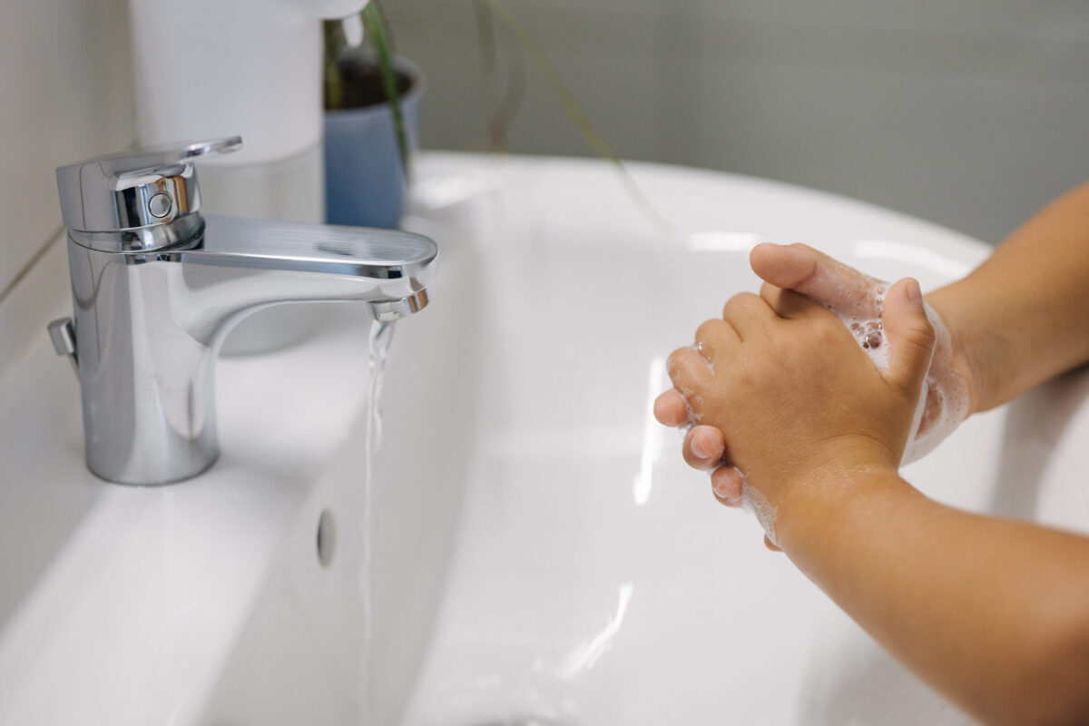 8 Ways to Avoid Food Poisoning 2 Little girl wash hand after school. White and clean bathroom. Automatic soap dispenser in the bathroom.