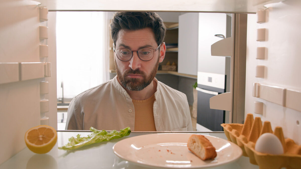 8 Common Potluck Problems and How to Solve Them Like a Pro 2 Man hungry guy open empty refrigerator with half lemon, nasty lettuce leaf, one egg, slice of bread order food delivery buying products with mobile phone deliver app point of view from inside fridge