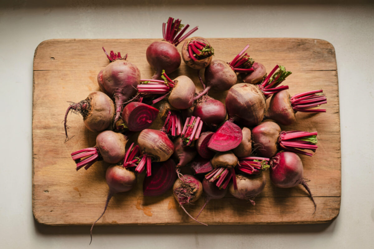 10 Vegetables You Won’t Find on My Plate—And Why I Skip Them Every Time 2 A rustic wooden board holds a pile of vibrant red beetroots, some whole and others halved, showcasing their earthy tones and fresh stems.