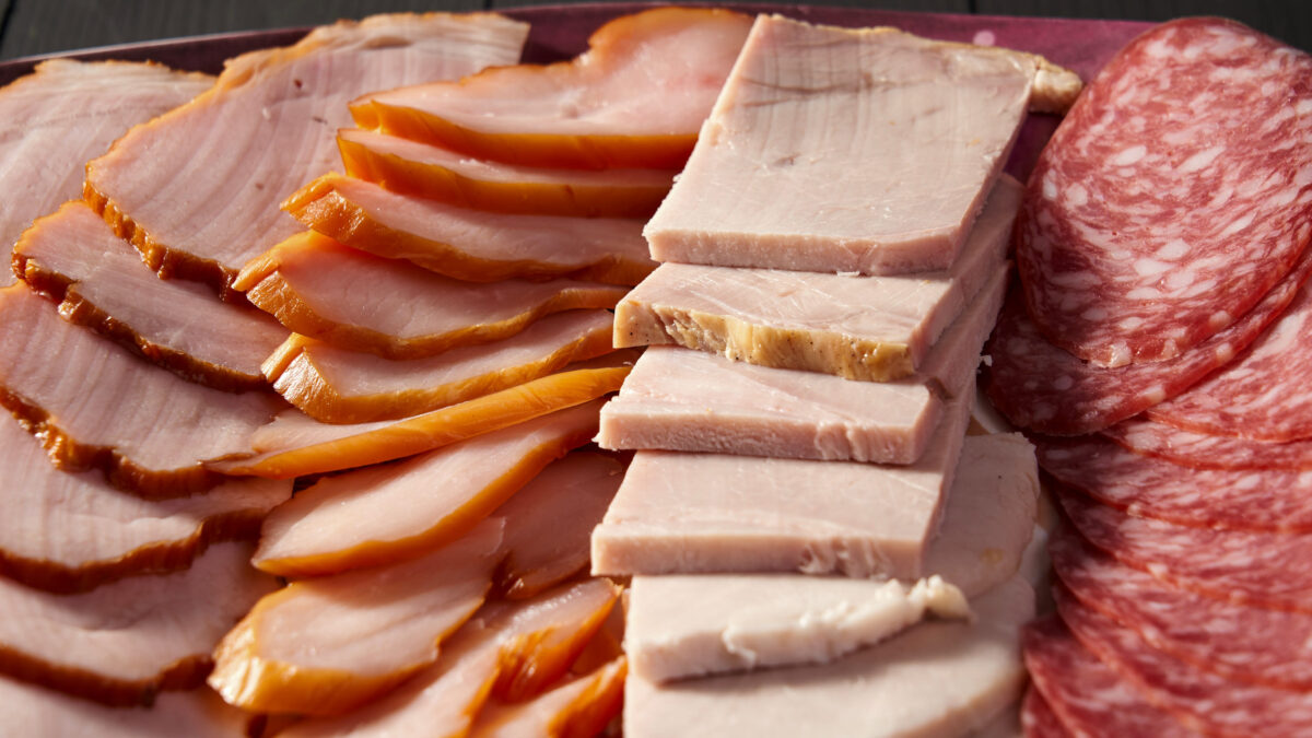 Top Foods to Avoid When Managing High Cholesterol for a Healthier Heart 3 A plate of meat and cheese with a slice of ham on top. The ham is cut into small pieces and is surrounded by other meats and cheese