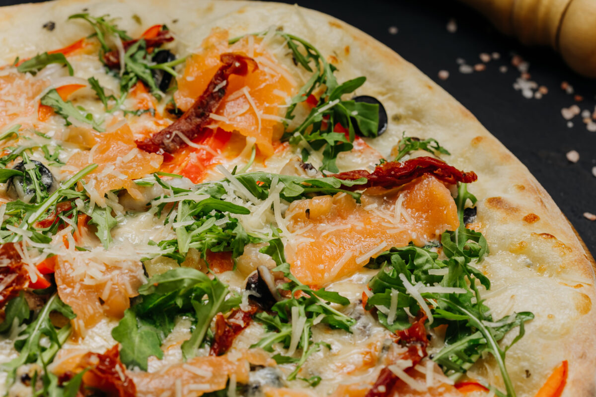 The Most Expensive Pizzas in America 2 Gourmet pizza with salmon arugula cheese and sun dried tomatoes on wooden board