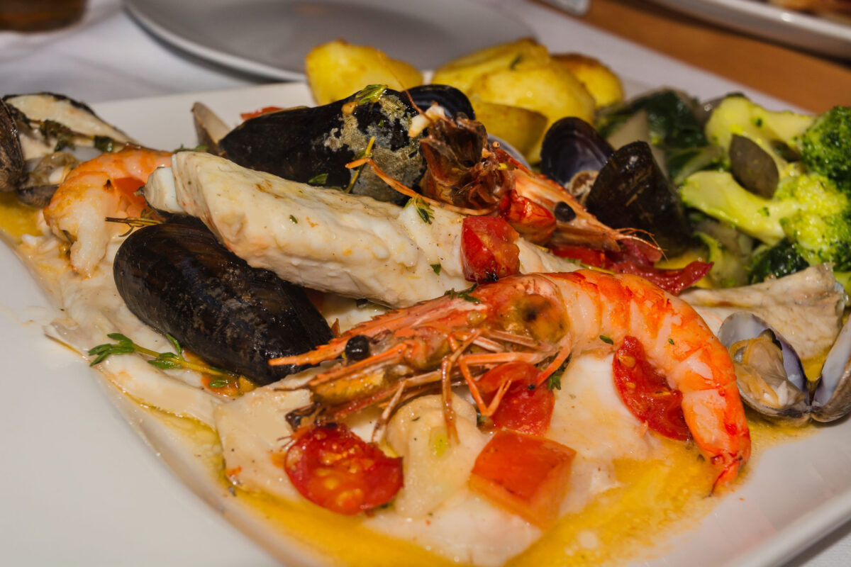 The Caloric Nightmare 3 Varied seafood, dorade, mussels and shrimps on a white plate.