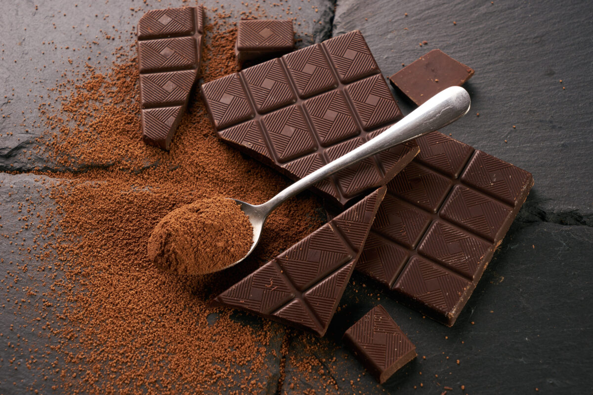 How These 6 “Age Defying” Foods Could Be Harming Your Skin 3 Silver spoon with cocoa powder and dark chocolate on dark slate table