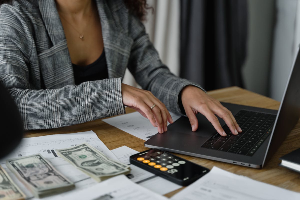 8 Money Myths That Are Actually Keeping You Poor 2 A businesswoman working on finance management with cash and calculator on desk.