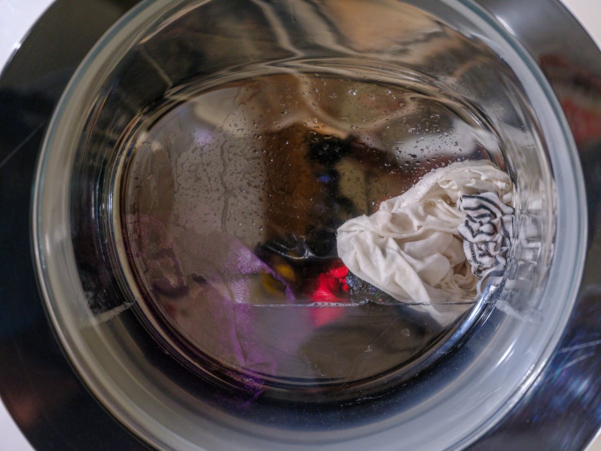 11 Laundry Mistakes to Avoid 2 A clear view of wet clothes spinning inside a front-loading washing machine.