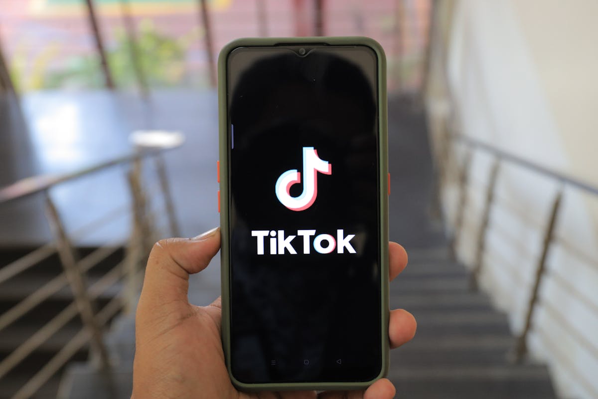7 Alarming U.S. Culture Wars That Are Getting Harder to Ignore 4 A close-up of a hand holding a smartphone displaying the TikTok app inside a modern building.