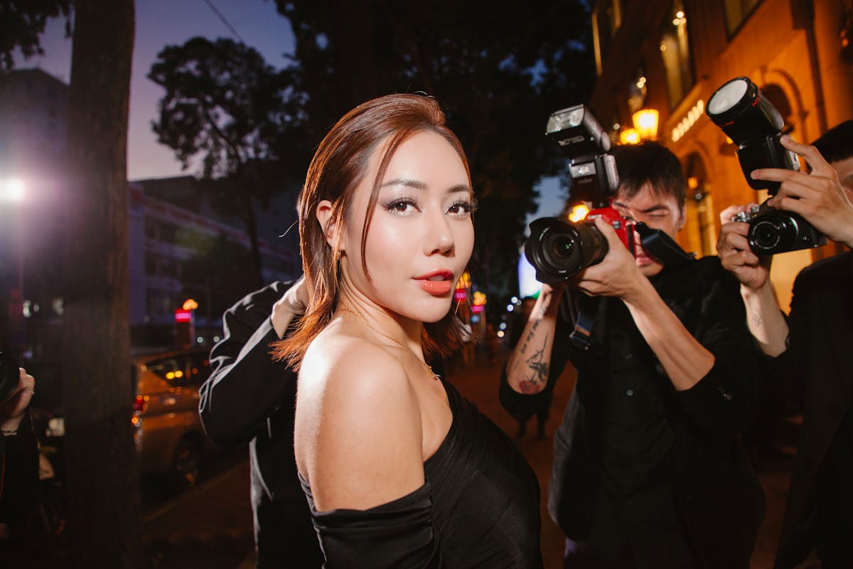 10 Shocking Secrets That Reveal the Dark Side of Hollywood 1 A glamorous woman in black poses confidently for photographers at a night event.