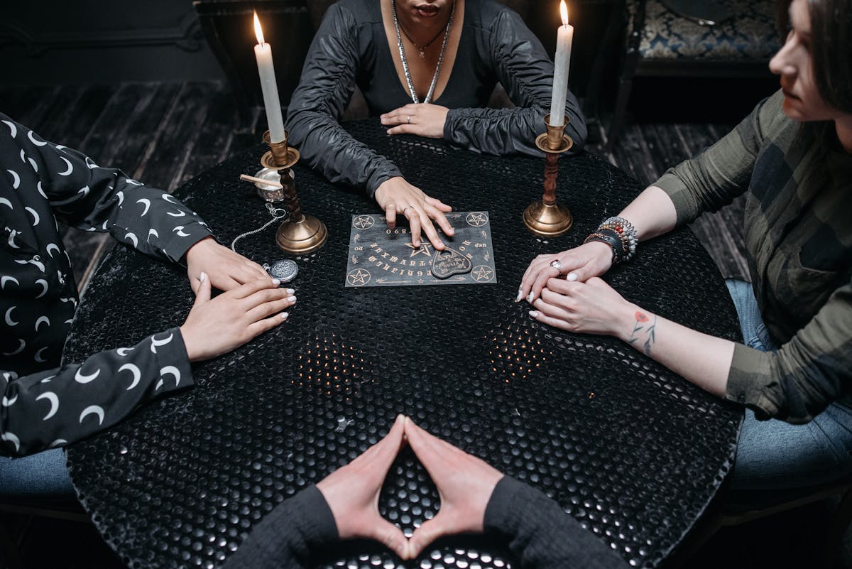 6 Weird Celebrity Wills and Final Wishes That Still Shock Us 4 A group of adults engage in a mysterious seance using a Ouija board by candlelight.