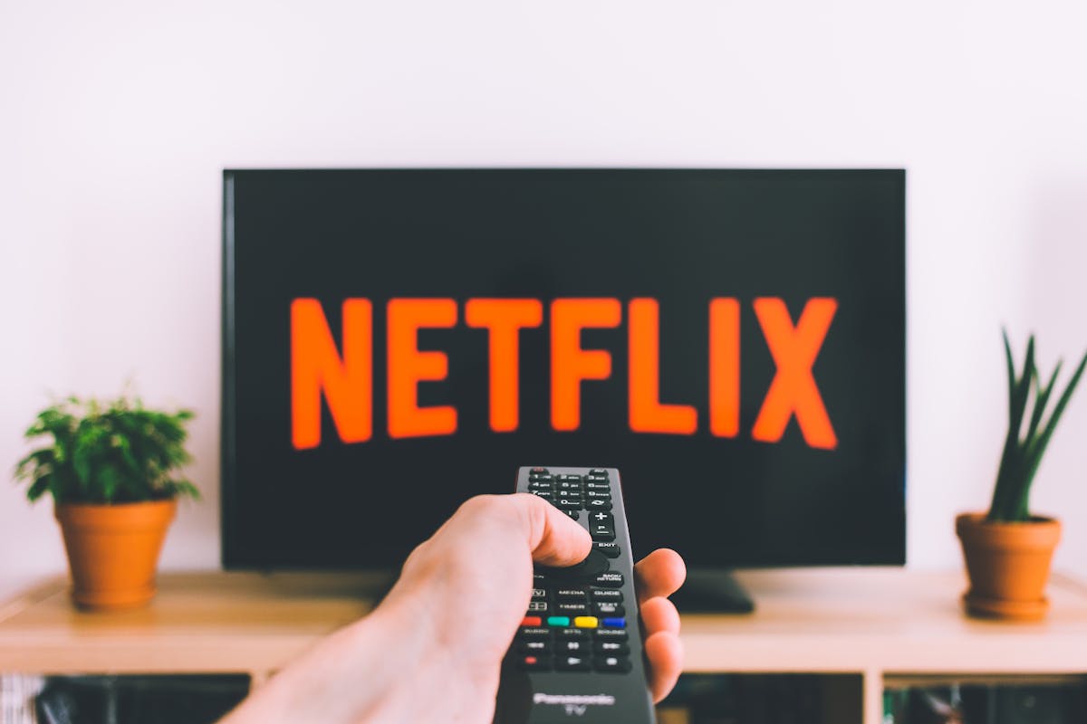 The 10 Most Unusual Jobs You Won’t Believe Exist 4 A hand holding a TV remote in front of a screen with Netflix, perfect for streaming and movie night themes.