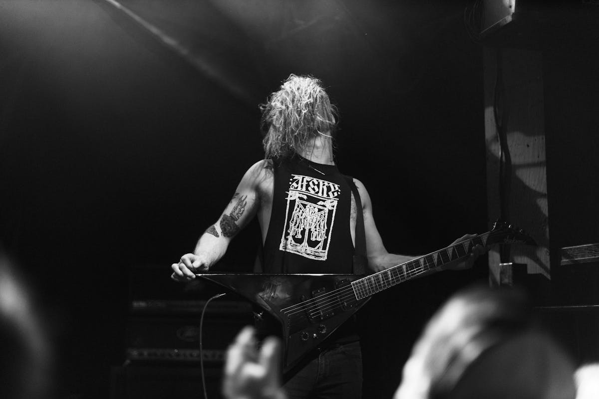 10 Heavy Metal Scandals That Shaped the Genre 4 A powerful black and white image of a guitarist performing energetically on stage, creating an electrifying concert atmosphere.