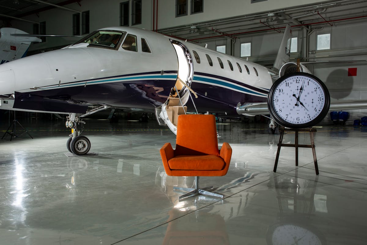 10 Strange Reasons People Have Borrowed Money 4 A private jet and modern furnishings inside an illuminated airport hangar.