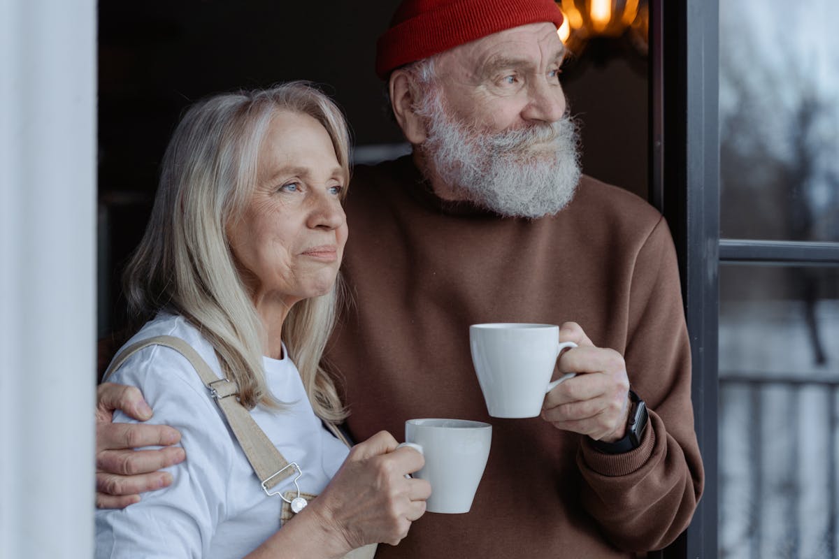 You’re Probably Broke Because of These 6 Hidden Financial Pressures 4 A senior couple embraces while enjoying coffee, symbolizing love and companionship.