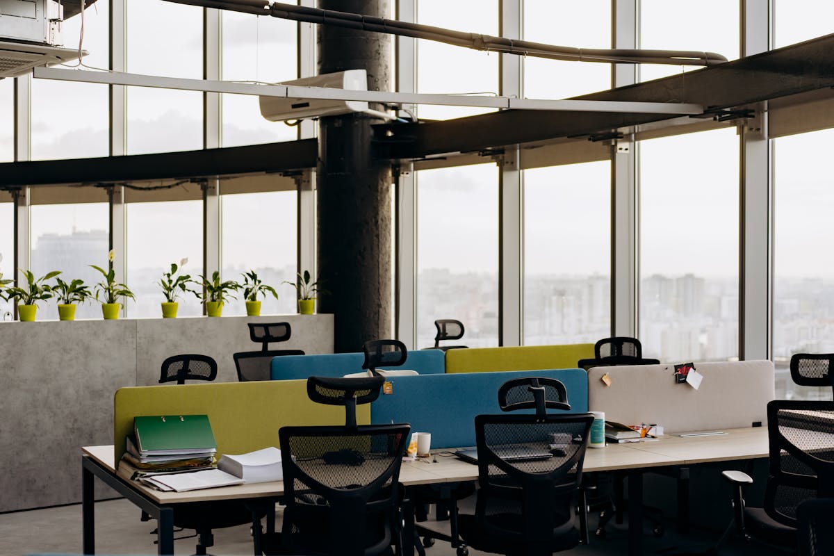 10 Ways People Got Paid to Do Nothing 3 A spacious open office with colorful dividers, large windows, and a cityscape view, perfect for creative work environments.