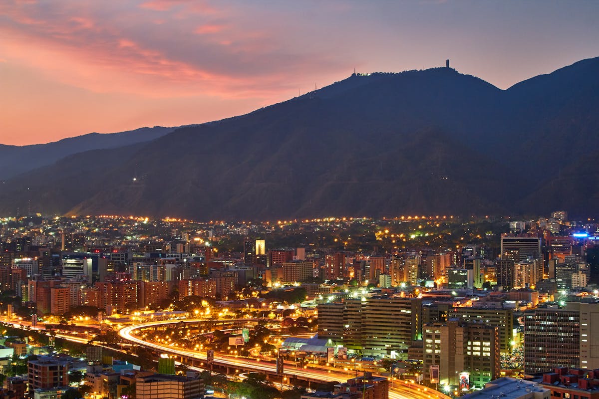 10 Most Dangerous Cities in the World to Avoid in 2026 2 A stunning aerial view of Caracas cityscape at dusk, showcasing the vibrant city lights against the mountainous backdrop.
