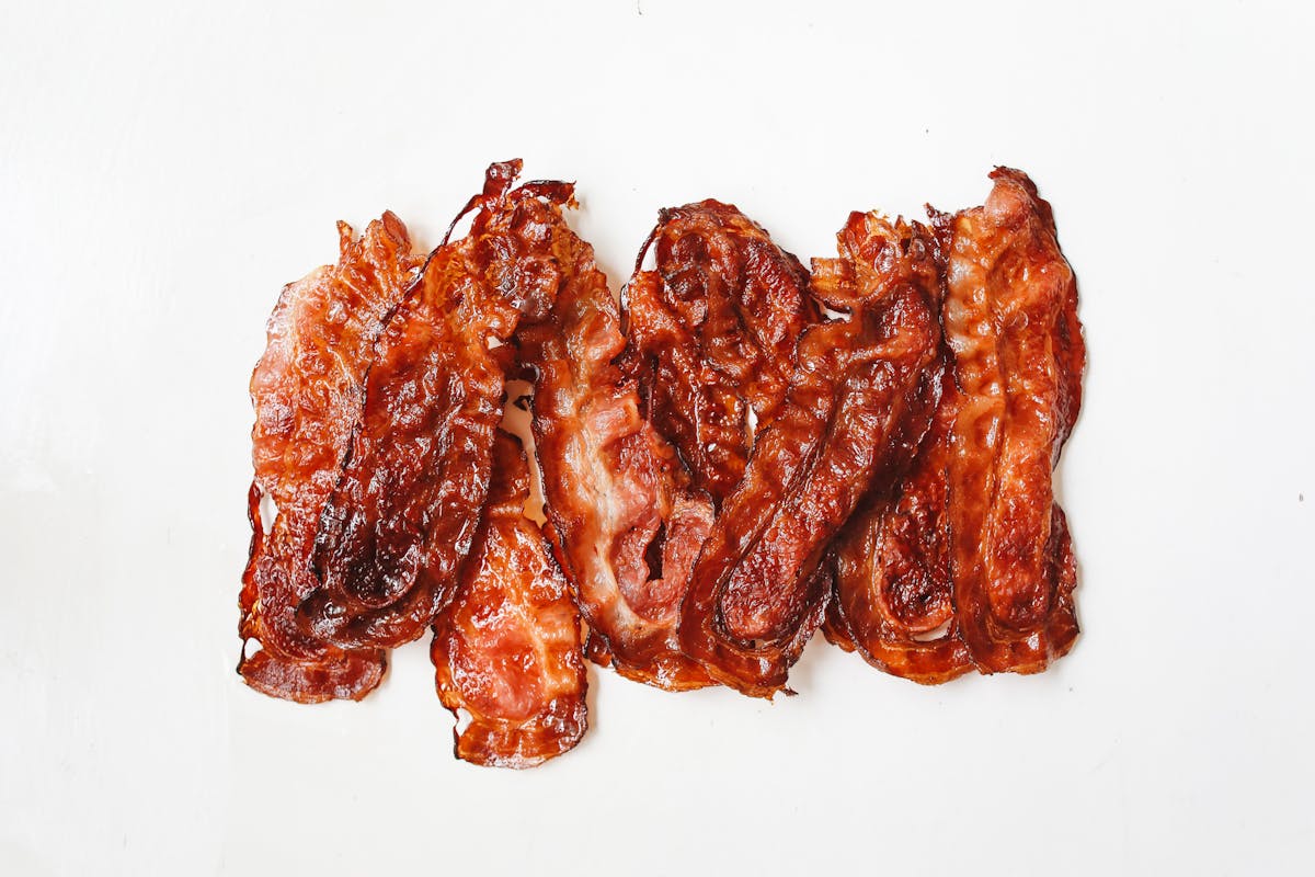 Stop Eating These 10 Foods If You Have High Cholesterol 1 A tempting display of crispy bacon strips, perfect for breakfast or a savory treat.