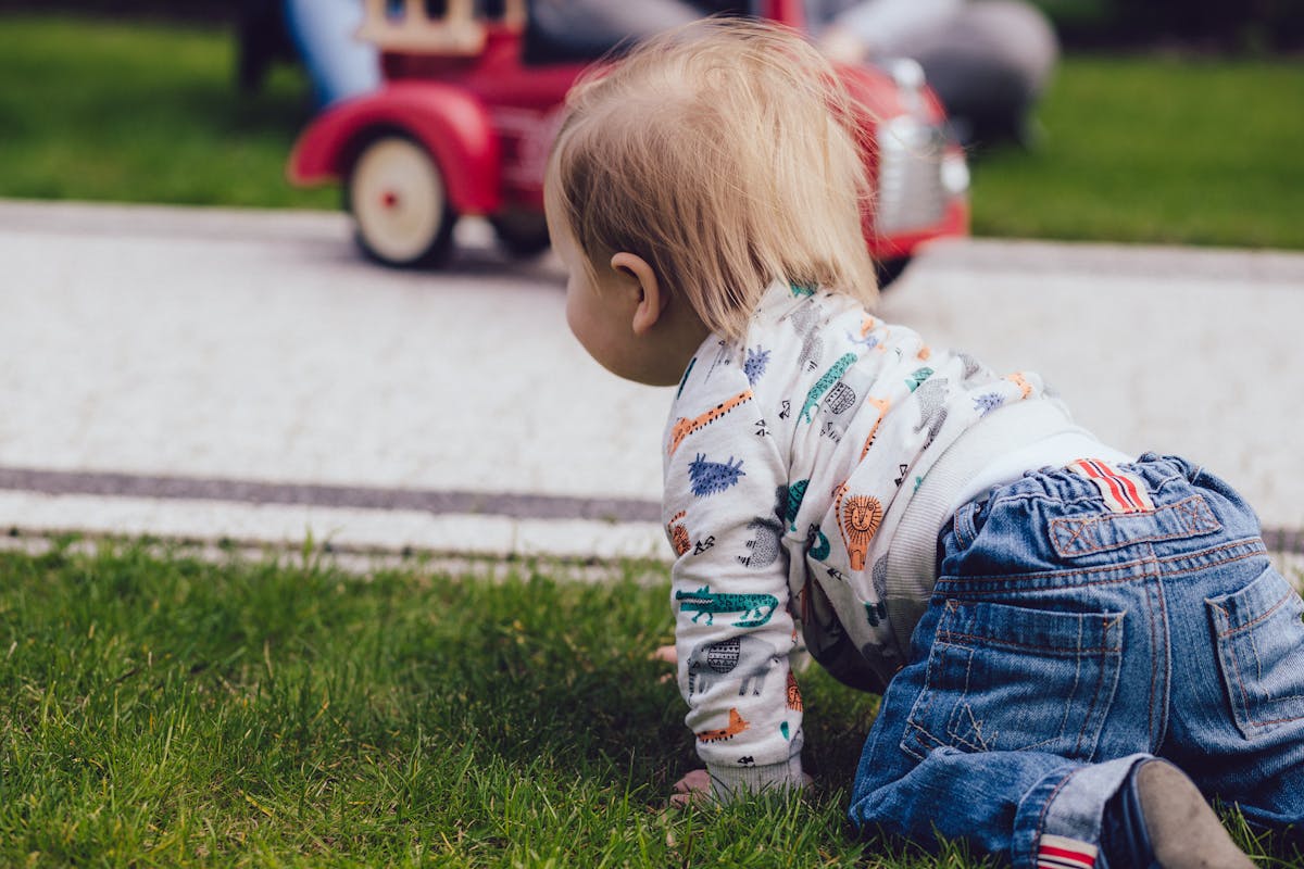 10 Bizarre and Unbelievable Competitions From Around the World 1 A toddler crawling on green grass outdoors near a toy car, enjoying a sunny day.