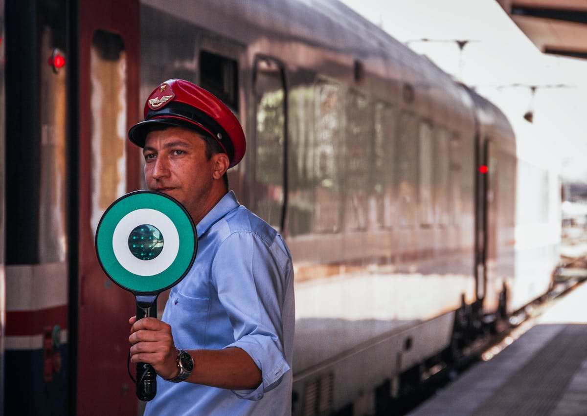 The 10 Most Unusual Jobs You Won’t Believe Exist 2 A train conductor at a station holding a signal for train departure.