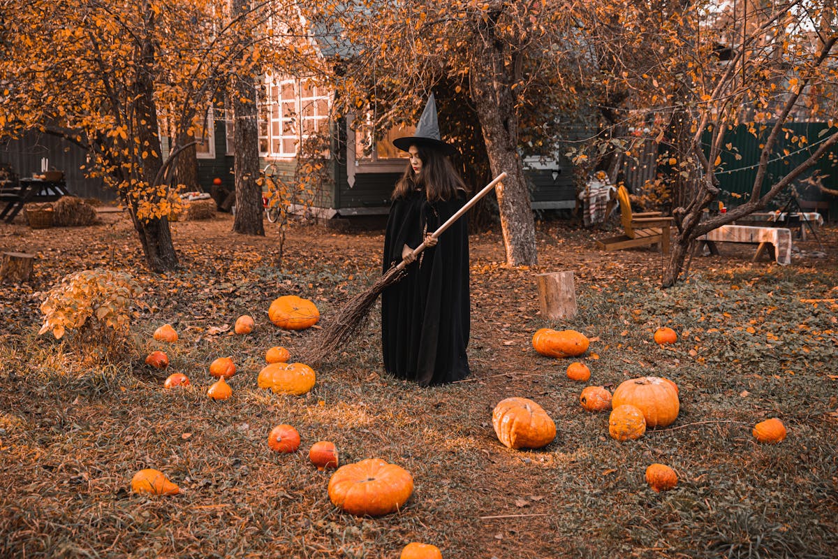 9 Strange Things People Blamed for Natural Disasters Before Science Changed the Story 3 A witch in a classic costume stands among pumpkins in a fall-themed backyard, creating a perfect Halloween vibe.