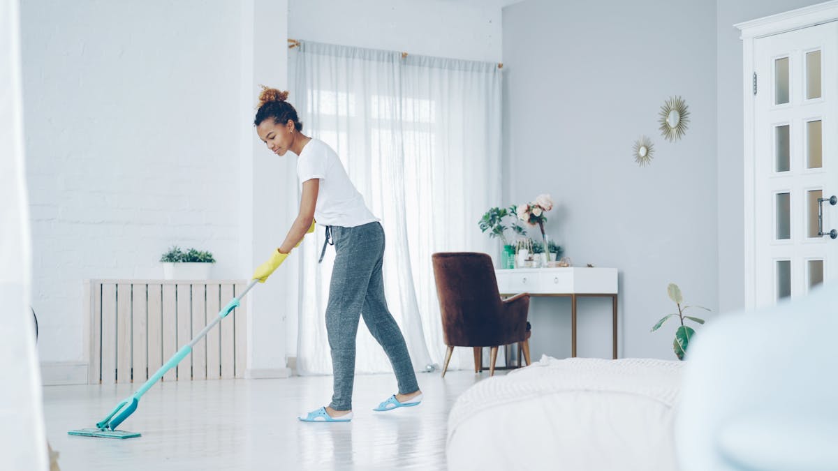 15 Cleaning Products You Should Avoid at All Costs and What to Use Instead 3 A woman cleaning a bright, modern living room with a mop, creating a clean, welcoming space.