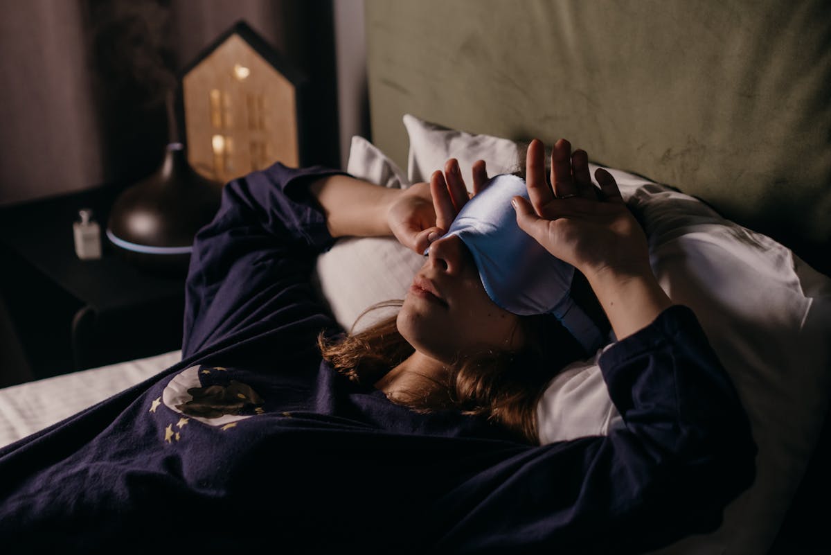These 6 Daily Habits Are Quietly Destroying Your Mental Health 3 A woman in comfortable attire rests indoors wearing a sleep mask, exuding a cozy and peaceful mood.