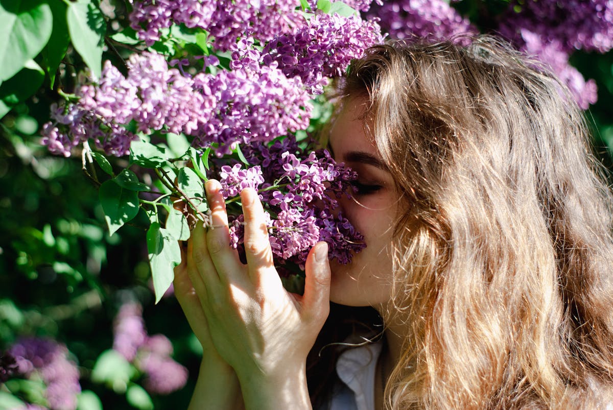 10 Common Allergies That You Shouldn’t Ignore 1 A young woman relishes the scent of lilac flowers in a sunlit garden, embodying spring and relaxation.
