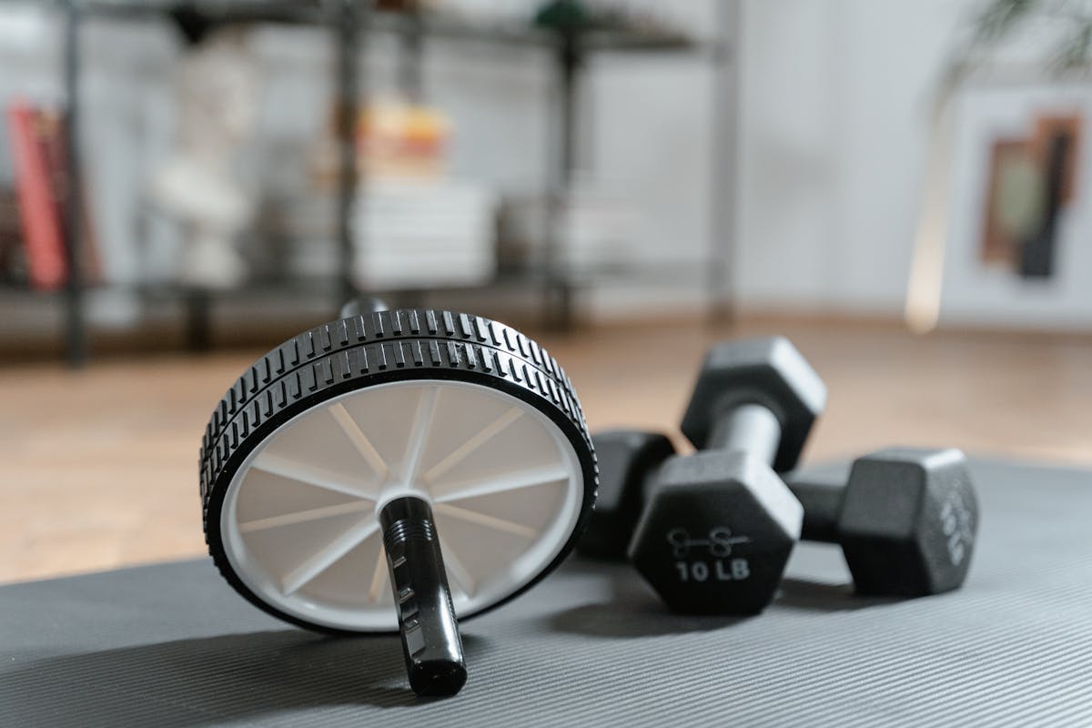 8 Motivation Mistakes That Are Killing Your Workout Routine 3 Ab roller and dumbbells on yoga mat, perfect for a home workout routine and healthy lifestyle.