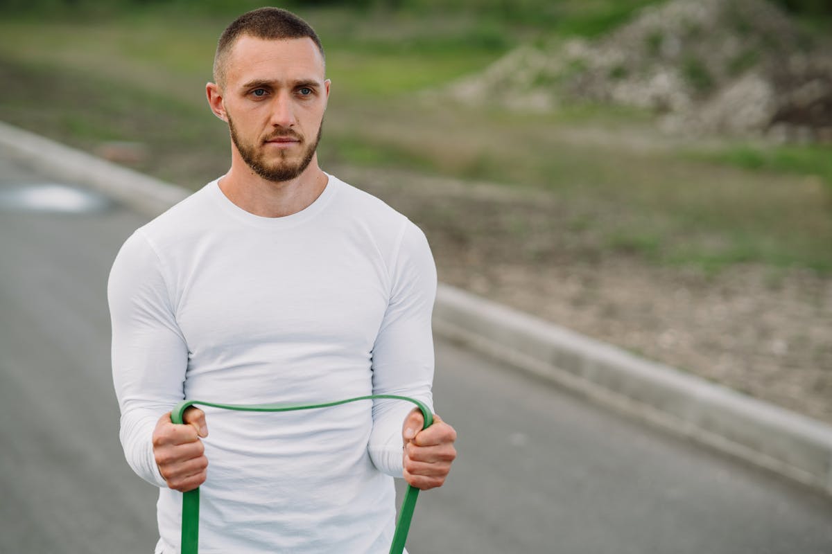 10 Office Exercises You Should Avoid If You Want to Stay Sluggish 4 Adult man working out with a resistance band on an outdoor road.
