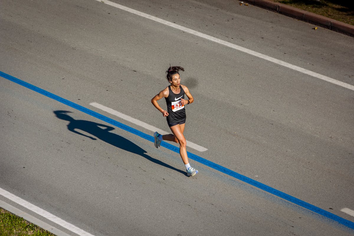 10 Everyday Activities That Can Alter Consciousness and Perception 1 Aerial view of a woman running in a marathon on a city street, capturing endurance and athleticism.