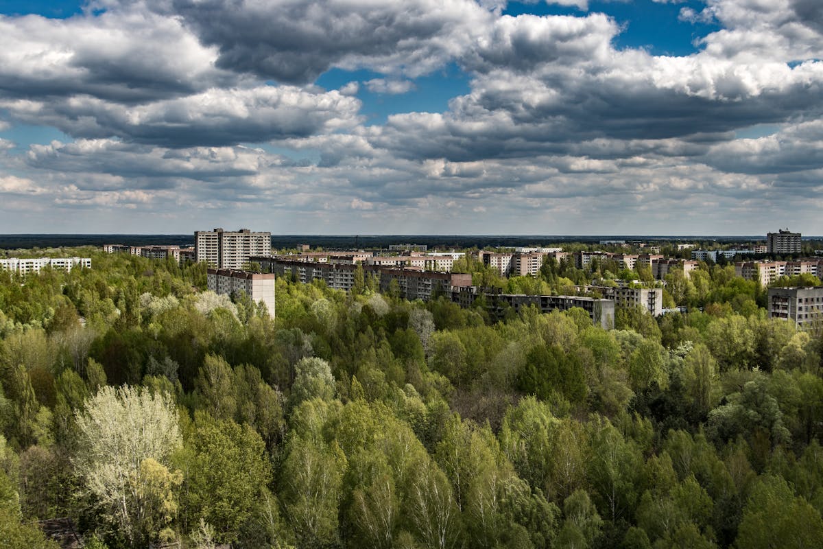 The 10 Most Polluted Places on Earth and Their Toxic Legacies 1 Aerial view of Pripyat in Chernobyl zone, showing abandoned buildings amidst vast greenery.