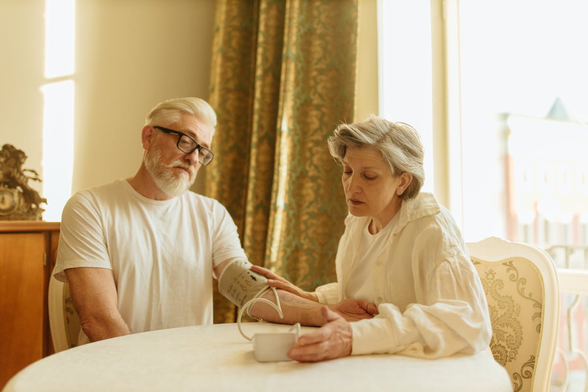 9 Dangerous Health Conditions Affecting People Over 60 3 An elderly couple at home measuring blood pressure with a digital monitor, depicting care and health awareness.