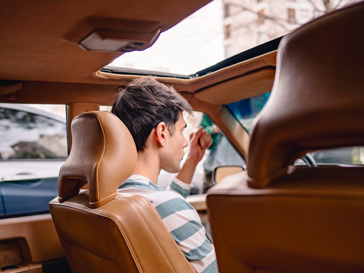 10 Bizarre Explosions That Will Leave You Speechless 3 Back view of a young man sitting in a vintage car with a sunroof, enjoying a sunny day.