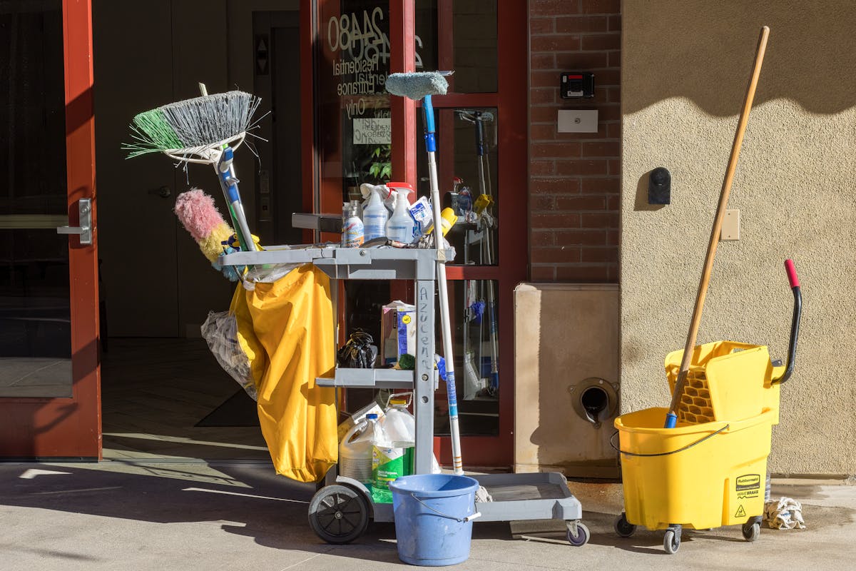 8 Items You Should Stop Storing In Kitchen Cabinets 4 Cleaning supplies and tools outside a building entrance bathed in sunlight.