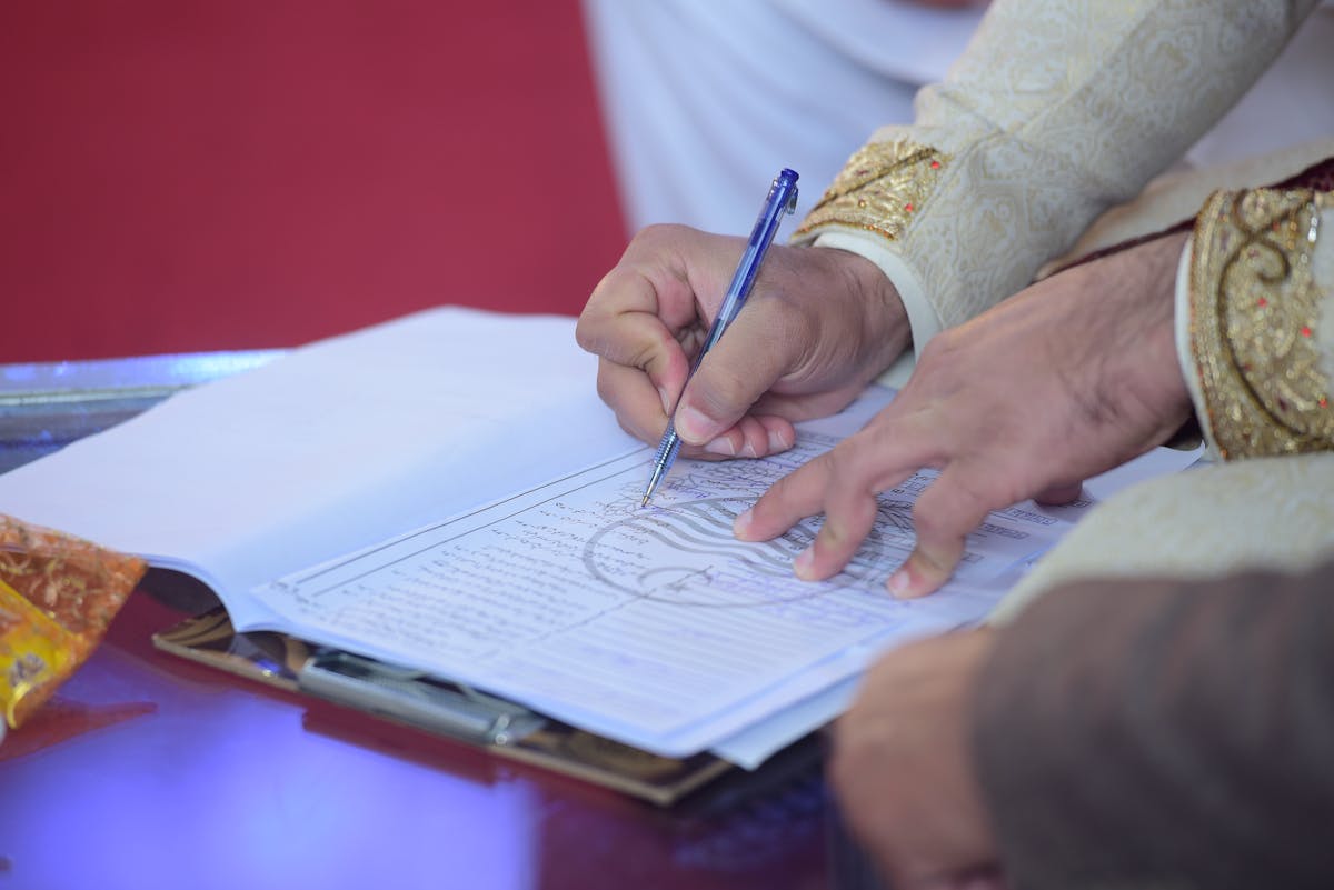 10 Weird Marriage Laws That Are Still Real in 2026 1 Close-up of a groom signing the marriage contract during a traditional Pakistani wedding ceremony.