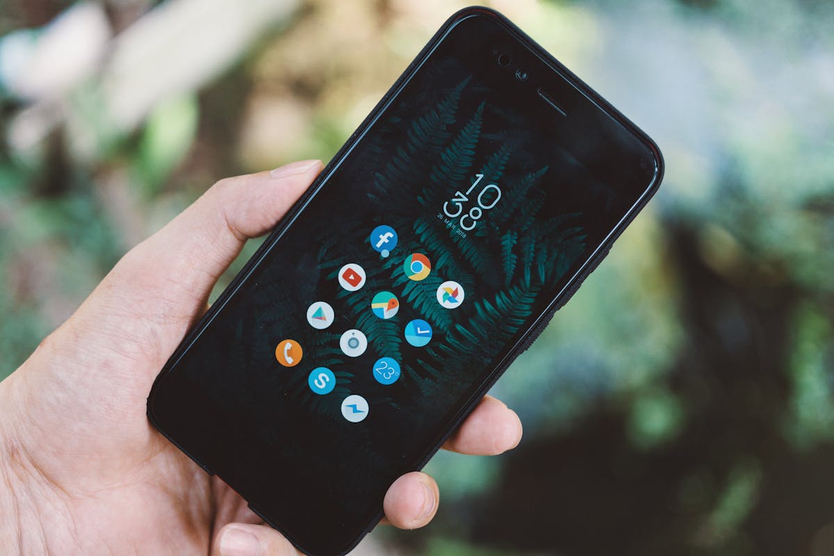 10 Things You’re Ruining by Cleaning Them With Disinfecting Wipes 2 Close-up of a hand holding a smartphone with app icons and a nature wallpaper.