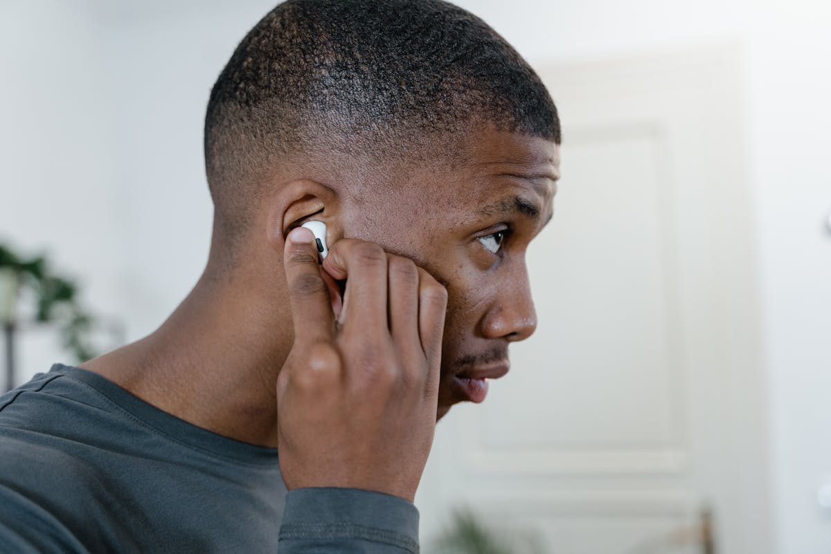 Stop Using These 11 Everyday Items the Wrong Way 4 Close-up of a man adjusting his wireless earbuds while indoors, showcasing modern lifestyle.