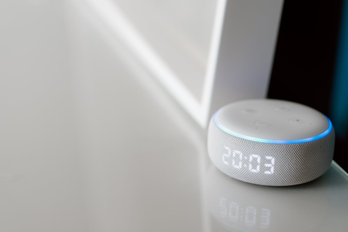 10 Everyday Items That Didn’t Exist 15 Years Ago But Now Define Modern Life 1 Close-up of a smart speaker with a digital clock display on a minimalist surface.
