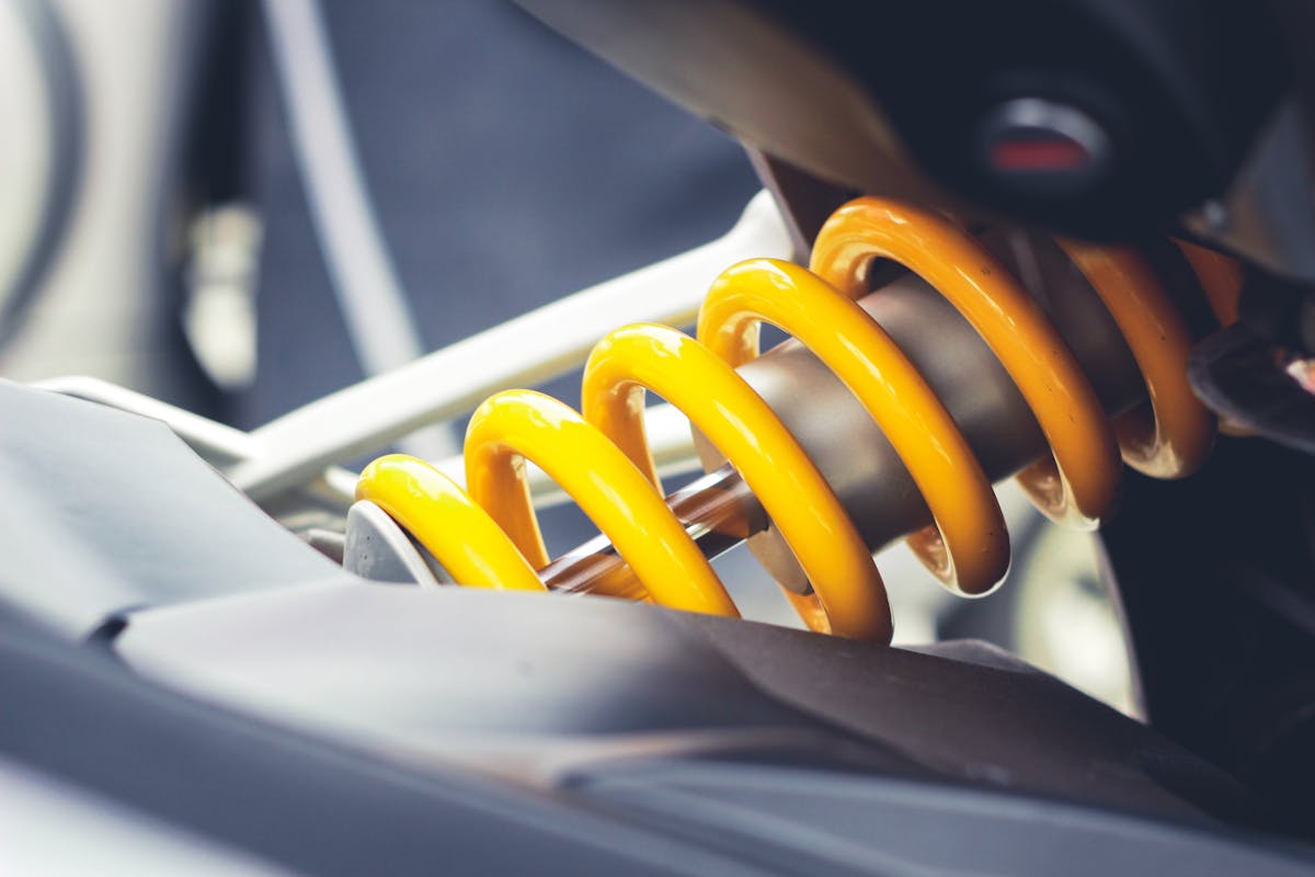 Don't Attempt These 5 Car Maintenance Tasks Unless You Are A Professional 2 Close-up of a vibrant yellow coil spring, showcasing mechanical engineering details.