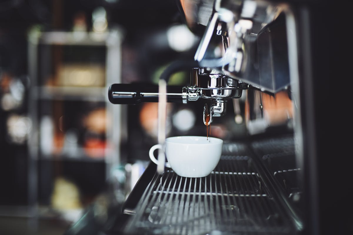 10 Bizarre Addictions That Highlight the Power of the Brain 3 Close-up of espresso machine brewing coffee into a white cup in a cafe setting.