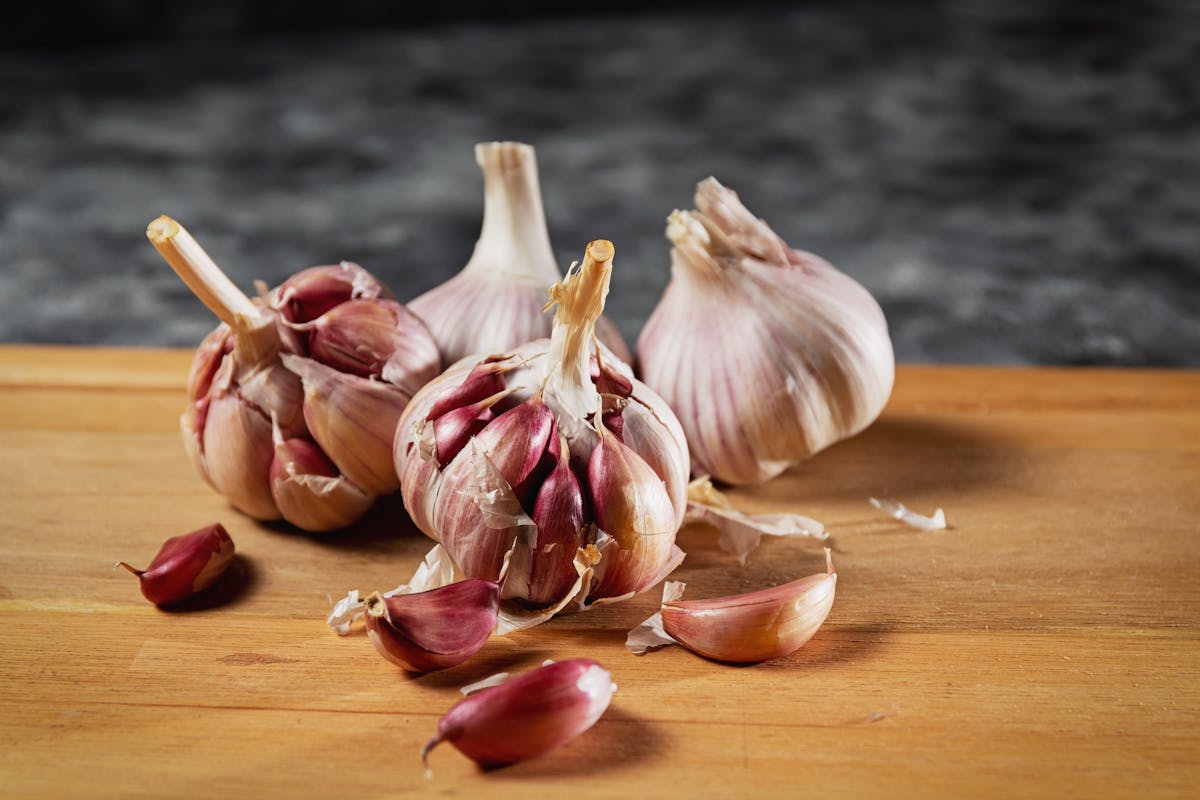 You Might Be Smelling Bad Because of These 10 Common Foods 1 Close-up of fresh garlic bulbs and cloves on a wooden cutting board.