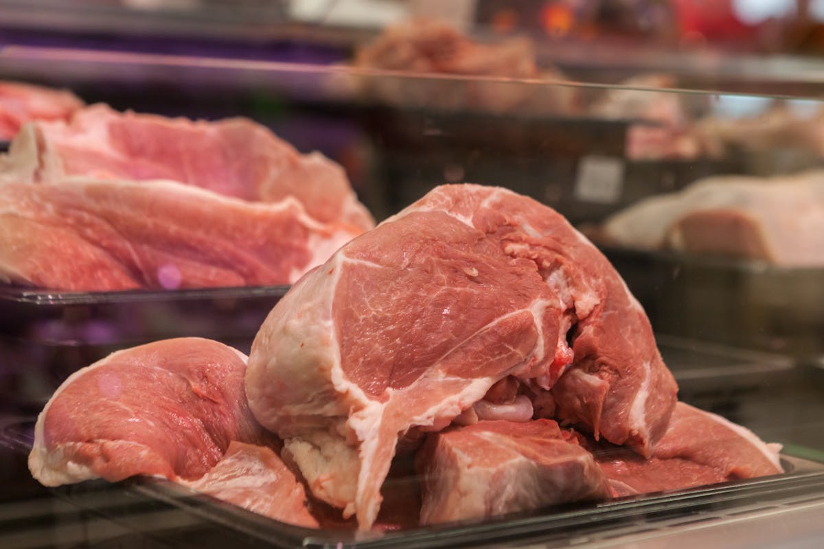 These 10 Morning Foods Are Silently Destroying Your Body 4 Close-up of fresh raw pork cuts on display in a glass case at a market.