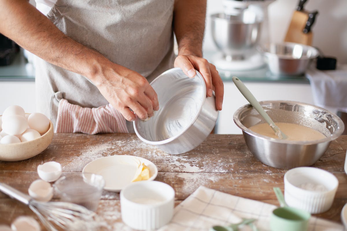 Unveiling the Strange Ingredients Hiding in Your Everyday Foods and Products 1 Close-up of hands greasing a pan with ingredients ready for baking in a kitchen.