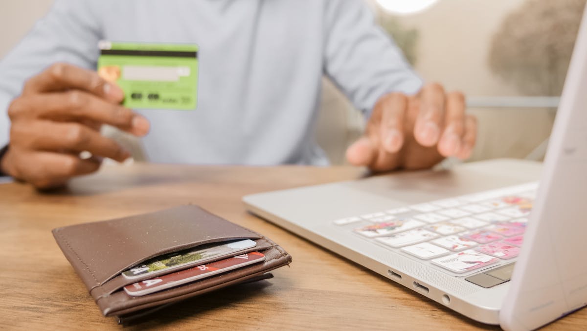 10 Bizarre Schemes Corporations Have Tried To Get Away With 2 Close-up of hands with a bank card and laptop for online shopping. Perfect for illustrating e-commerce concepts.
